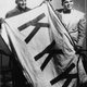 Two Lumbee men, Charlie Warriax (left) and Simeon Oxendine (right), displaying the KKK flag they stole from the Klan following their victory in the Battle of Hayes Pond.
